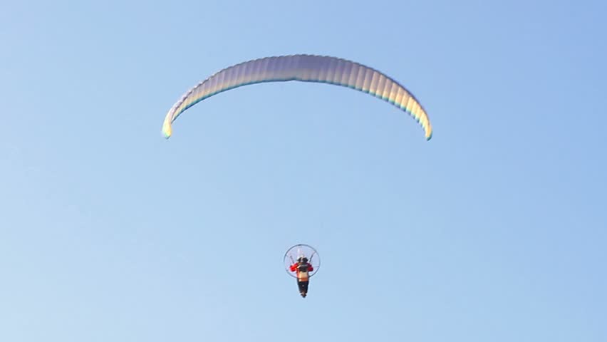 Powered paraglider, paramotor flying over the blue sky
