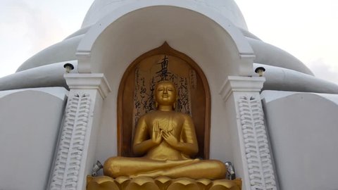 Close approach to buddhist stupa with golden Buddha statue