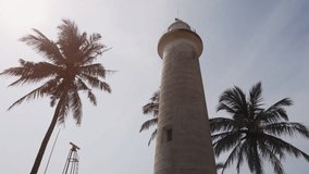 Beautiful. Cylindrical lighthouse tower. Built over the old Galle Fort. with tropical palm trees against the sky. 4k UHD stock video.