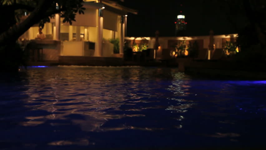 Water Surface of a Swimming Pool at night with light reflections and a bar in