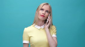 Tired unhappy woman talking on mobile phone without interest isolated over blue