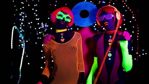 4k fantastic video of 3 sexy cyber glow ravers filmed in fluorescent clothing under UV black light. 2 cool women and a guy with a circular head