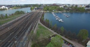 Aerial view drone footage of Helsinki area near central railway station, gardens and rail tracks with trains arriving and urban parks and water channel view in the capital of Finland, northern Europe