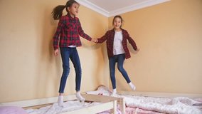 Slow motion video of happy teenage girls jumping on mattress at bedroom
