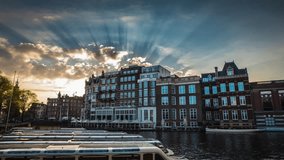 The most famous canals and embankments of Amsterdam city during sunset. General view of the cityscape and traditional Netherlands architecture. 4K Time Lapse Footage.