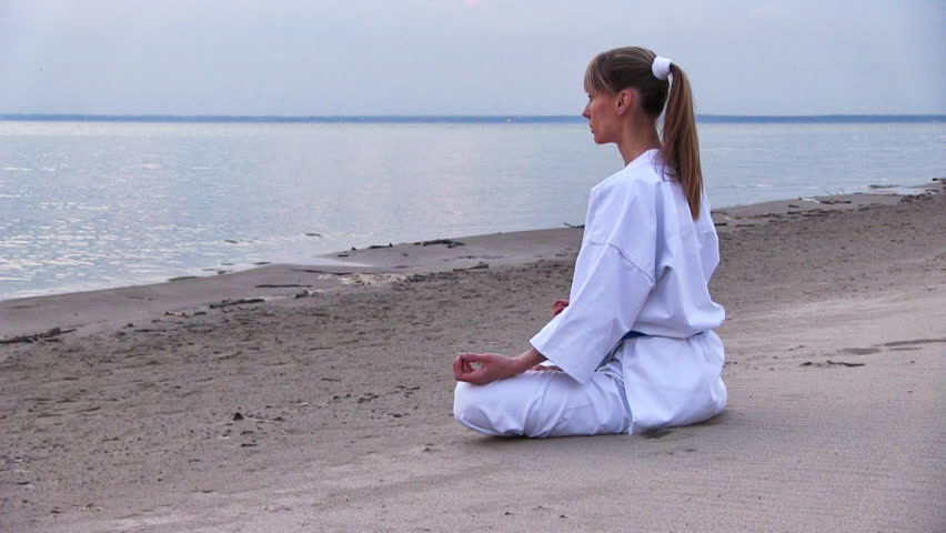 young woman meditation on sunset beach