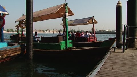 DUBAI, UAE - CIRCA 2008. Pan-right shot of an Abra, filled with commuters, docking. The labour force of the UAE is mainly made up of foreign workers from India, Asia and other Arab countries.