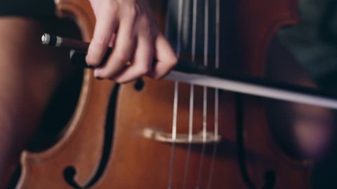 Woman hand playing violoncello with cello bow. Close up of female hand playing cello with cello bow. Cello playing music background