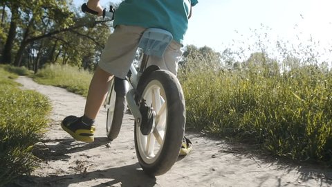 Back shot of kid riding the bicycle, close up sundown park slowmotion