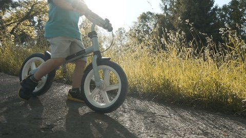 Little boy riding the bicycle against sun, park slowmotion shot