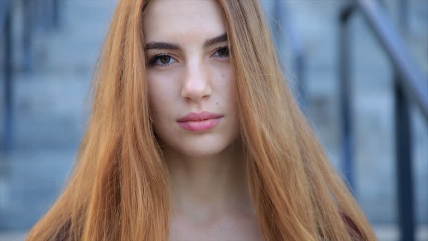 Portrait of beautiful angry sad young girl with long red hair. Slow motion