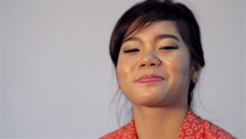 Young Asian woman smiling at the camera and looking happy.