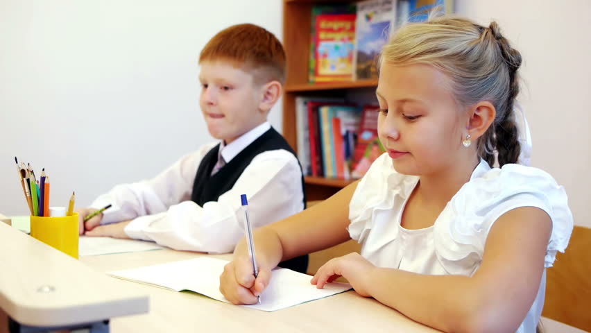 Schoolgirl writing her task and boy peeping