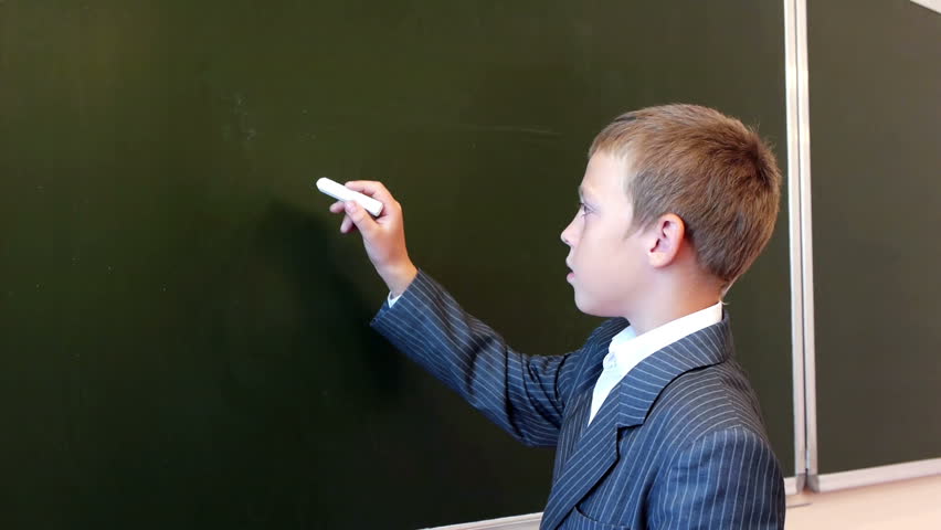 Serious schoolboy writing english alphabet on the blackboard