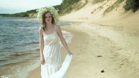 Woman In white dress staying on a beach with flower at the sunny day