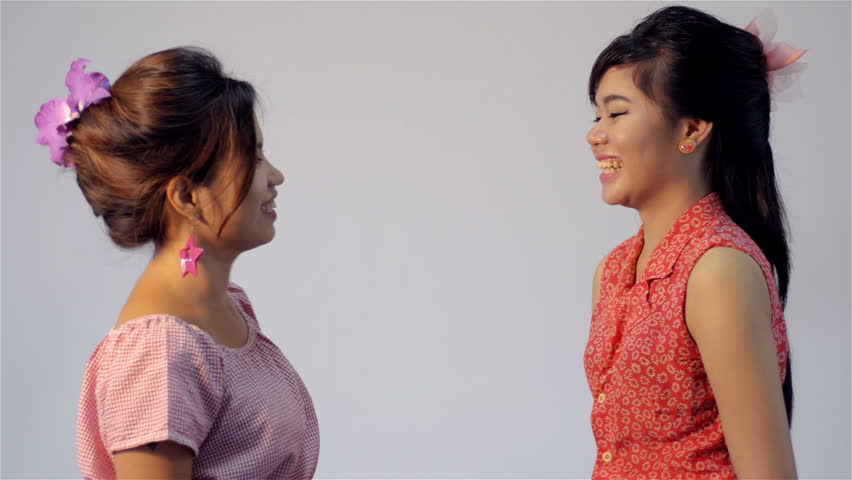 Two young Asian friends talking and laughing together - dolly in.