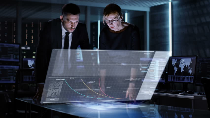 Male and Female Business Managers Use Touchscreen Interactive 3D Panel in Big Monitoring Room Full of Computers with Animated Screens.