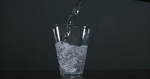 Water being poured into Glass against Black Background, Slow Motion 4K