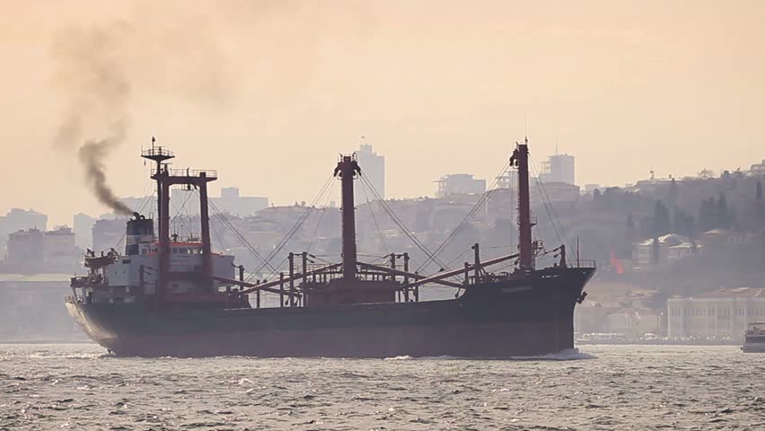 Marine air pollution. Istanbul in smog with a cargo ship
