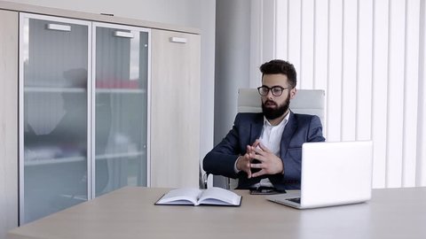 Serious businessman sitting in office and talking to someone