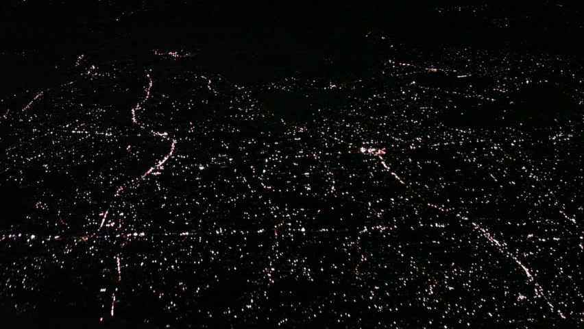 Flight over a crowded lit city, shot from a airliner at night.