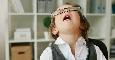 Portrait of caucasian beautiful young girl in glasses sneezing. Yong girl siting in modern office and sneezing. Indoor.