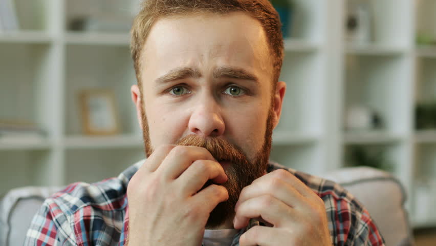 Portrait of man in stress sitting on the sofa at home in the living room and biting his nails because he feeling fear. Close up. Royalty-Free Stock Footage #27407197