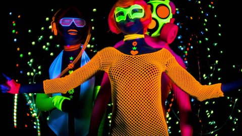 4k fantastic video of 3 sexy cyber glow ravers filmed in fluorescent clothing under UV black light. 2 cool women and a guy in a gasmask.