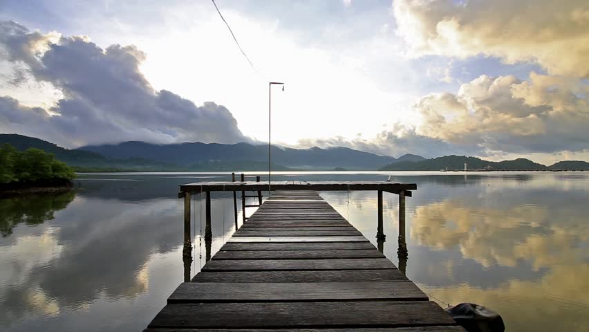 Scenic view of the wooden bridge to the sea. Against the backdrop of mountains and clouds.