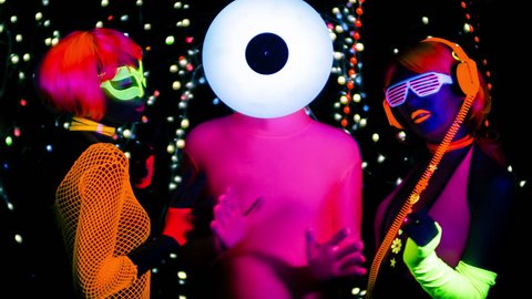 4k fantastic video of 3 sexy cyber glow ravers filmed in fluorescent clothing under UV black light. 2 cool women and a guy with a circular record vinyl head