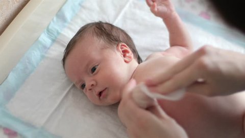 Mother is wiping baby with wet cotton pad