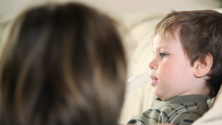 Sick little boy and mother using nebulizer to inhale the medicine panning