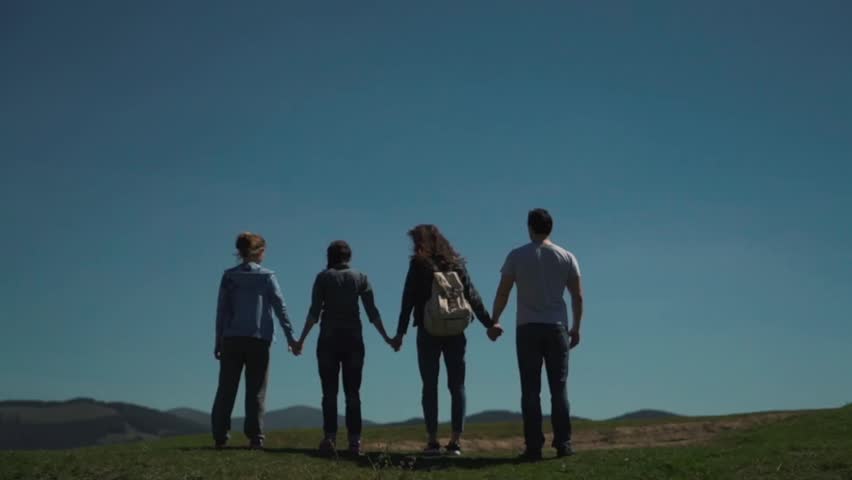 Friends rising hands up on the hill.