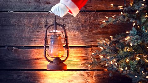 Santa Claus hand holding vintage oil lamp over Christmas holiday wooden rural background. Beautiful Empty Christmas room. New Year Background. Search, searching concept. 4K UHD video 3840X2160 