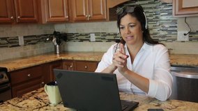 Middle aged woman working from home on laptop talking through her presentation on a video conference call