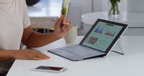 4K Thinking businesswoman looking at financial graphics on computer & drawing on screen with stylus pen