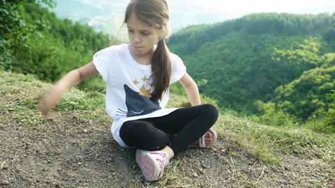 Angry kid on top of the hill with a green landscape behind her, 4K