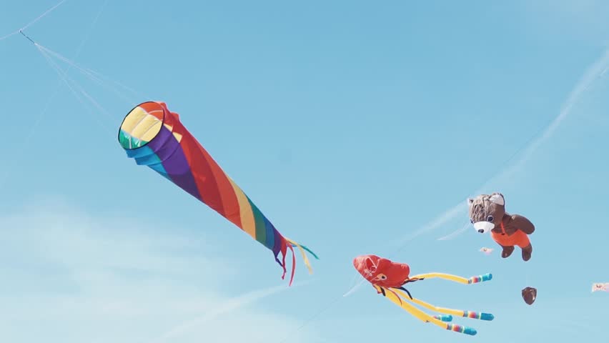 Many colourful kites in flight against blue sky and sunny day. Kite flying in the shape large rainbow flies in the sky Royalty-Free Stock Footage #27442141