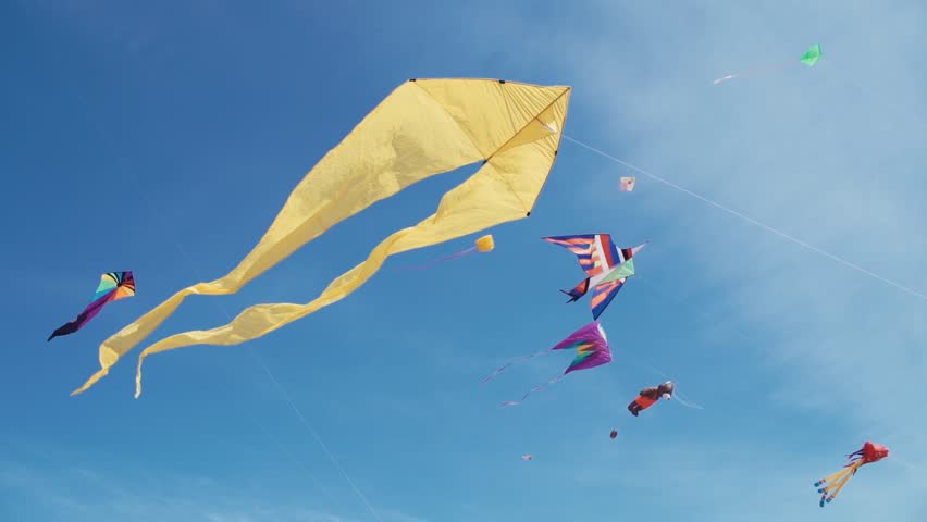 Many colourful kites in flight against blue sky and sunny day. Royalty-Free Stock Footage #27442240