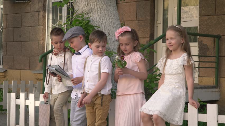 Small children the company sit on a small white fence