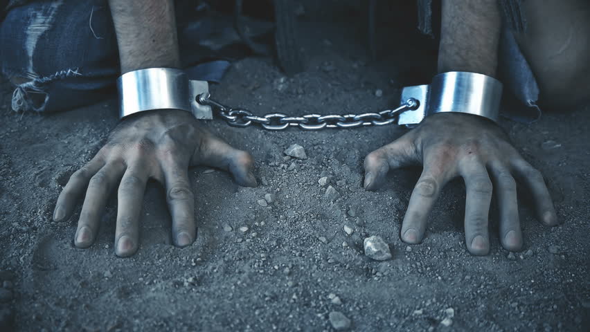 a prisoner in chains on his knees touching the dusty ground Royalty-Free Stock Footage #27462313