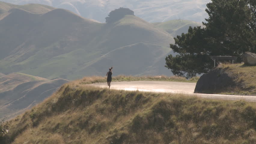 A runner going downhill on a country road.