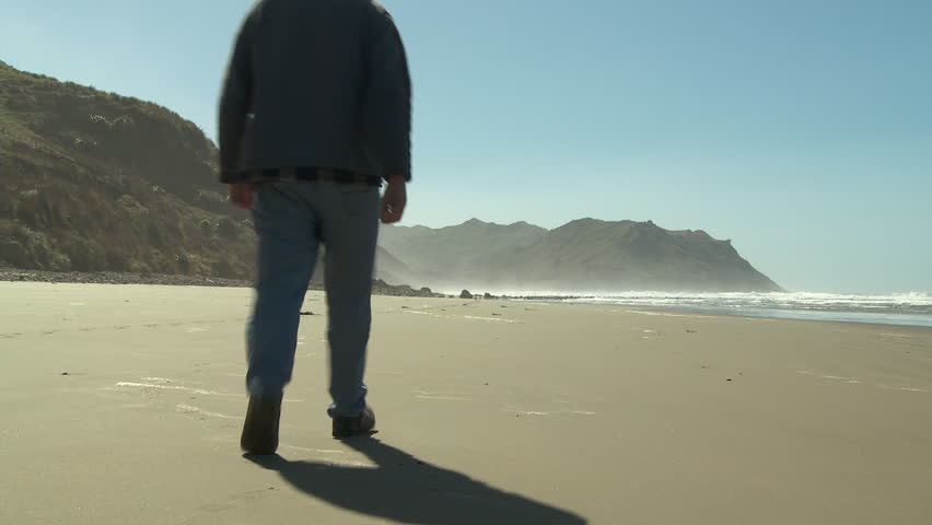 Man walking along a sandy, deserted beach
