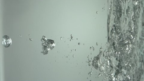 Water Splashes into Sideways Puddle - Water drops move sideways across a grey background and land in a vertical pool