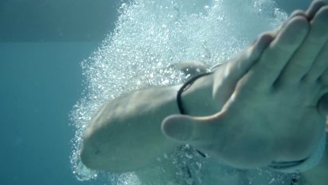 Slow-motion underwater Frontal CU of swimmer diving