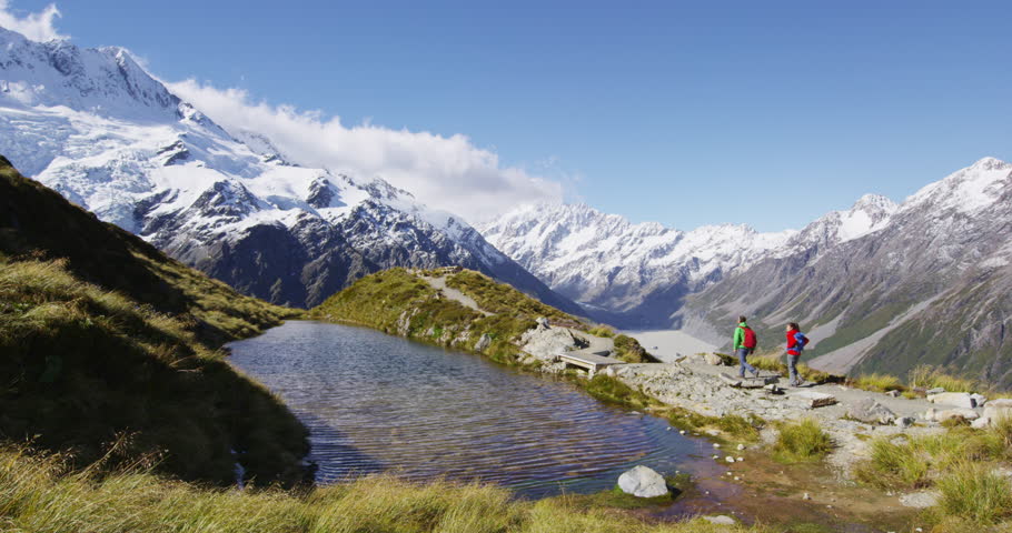 Hiking travel nature hikers in New Zealand mountains. Couple people walking on Sealy Tarns hike trail route with Mount Cook landscape, famous tourist attraction.