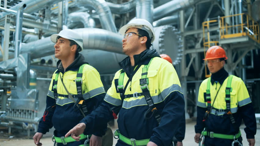 Team of workers walking on fuel plant
