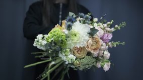 Close up of an unrecognizable woman in black clothes working in a florist shop holding a bunch of beautiful flowers. Locked down real time close up shot