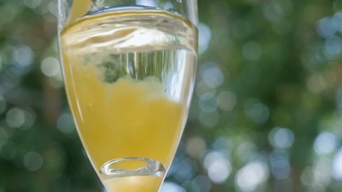 Orange juice pours into a glass of champagne making a mimosa cocktail at an outdoor bar. The alcoholic beverage is served during Sunday brunch as a bottomless option promoting day drinking and fun.