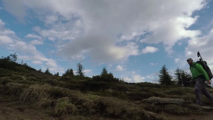 Slow motion of landscape photographer jumping over a rock on mountain trail